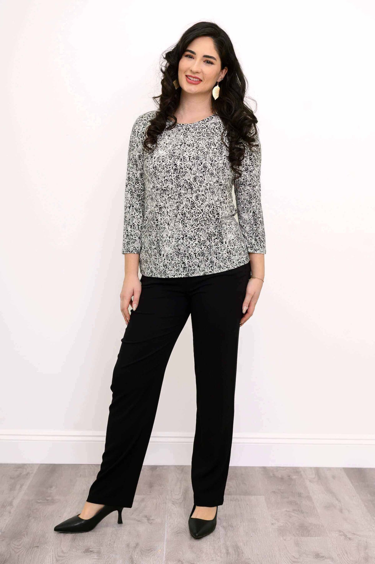 Full view of woman modeling a black and white graphic rose top with black pants