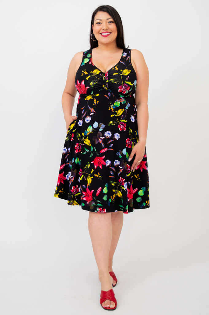 Woman in knee-length sleeveless black floral dress, front view