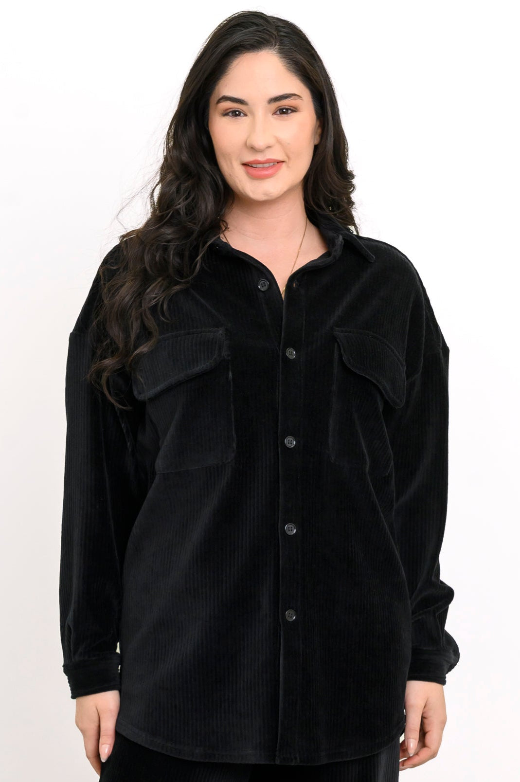 Front view of a woman wearing a black button-up corduroy shirt jacket with double flap pockets