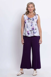 Full-length front view of model in sleeveless white and purple top and dark purple pants