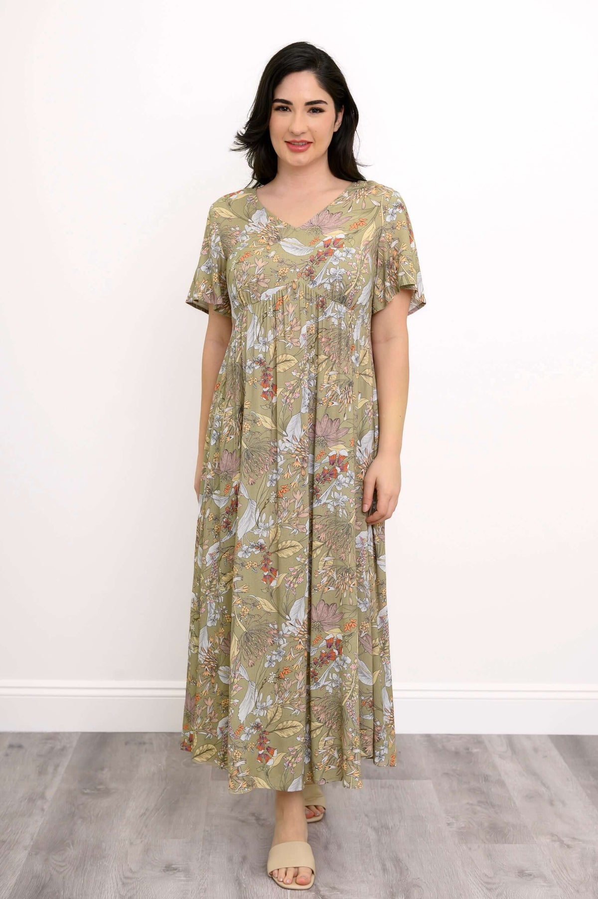 Woman wearing a green floral maxi dress with empire waist and flutter sleeves