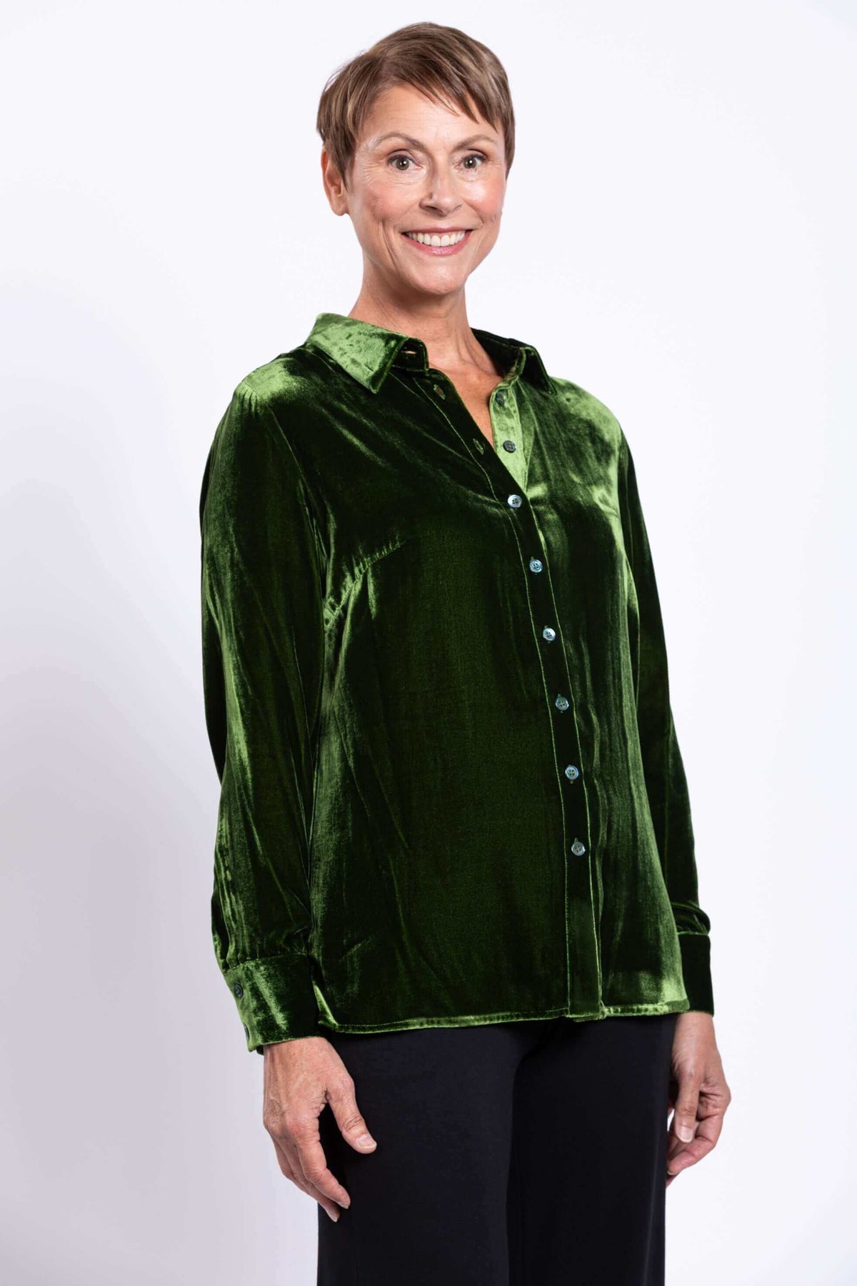 Woman wearing a green silk velvet blouse with a shirt collar and button cuff, front view