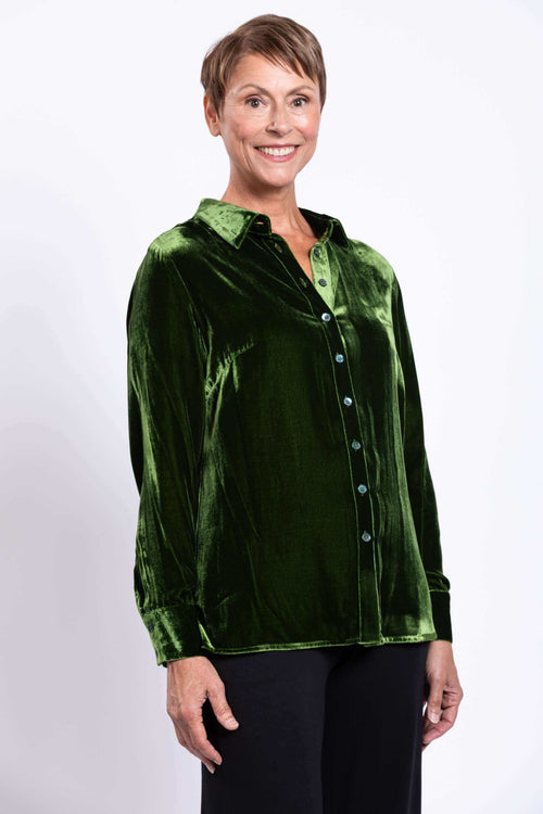 Woman wearing a green silk velvet blouse with a shirt collar and button cuff, front view