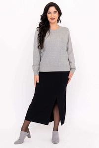 Woman in grey cable knit sweater paired with black skirt and grey booties