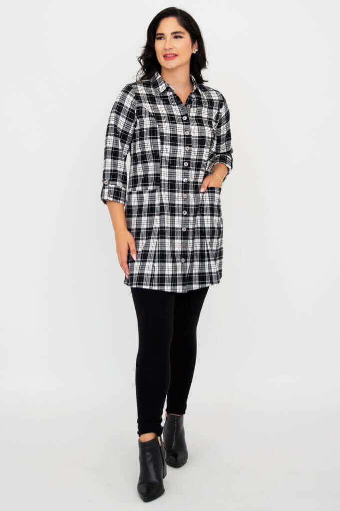 Model with hand in pocket wearing black and white plaid flannel tunic and black leggings
