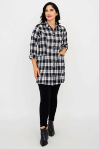 Model with hand in pocket wearing black and white plaid flannel tunic and black leggings