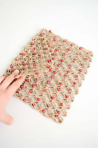 Hand holding flap of handwoven rattan purse with coral bead details