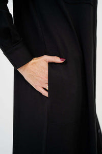 Close-up of hand in side pocket of long black duster coat