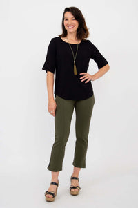 Woman posing hand on hip in black blouse and olive pants