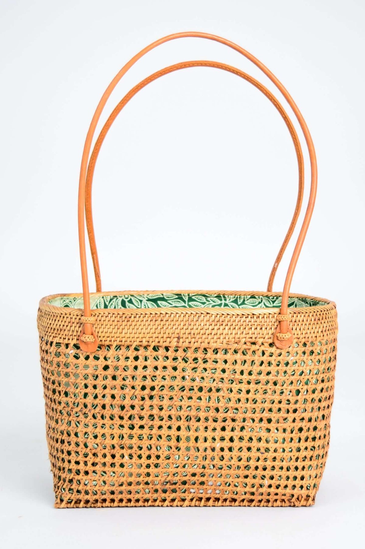 Hand woven rattan basket bag with green botanical lining and long leather handles