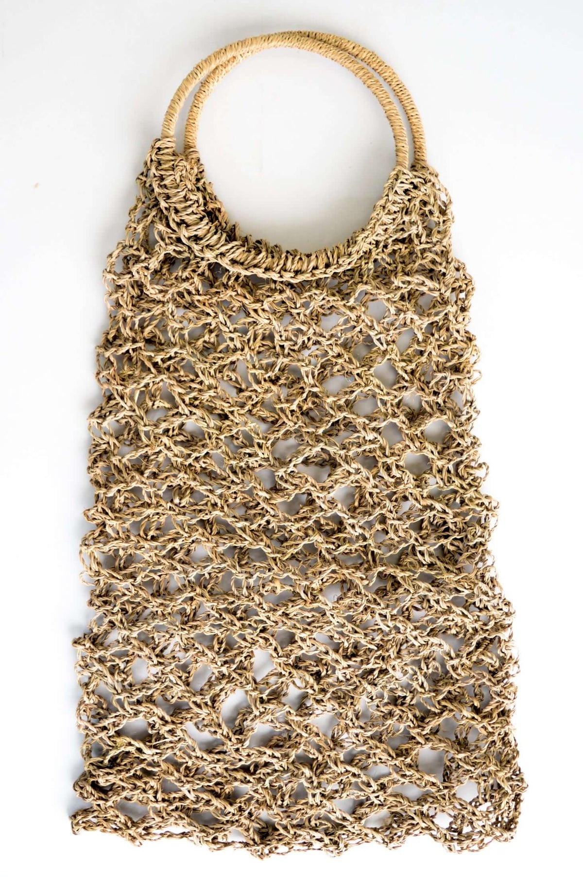 Hand woven net-like rattan tote bag with round handles on a white background