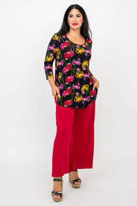 Model posing with hands in pockets, dressed in black floral bamboo top and red pants