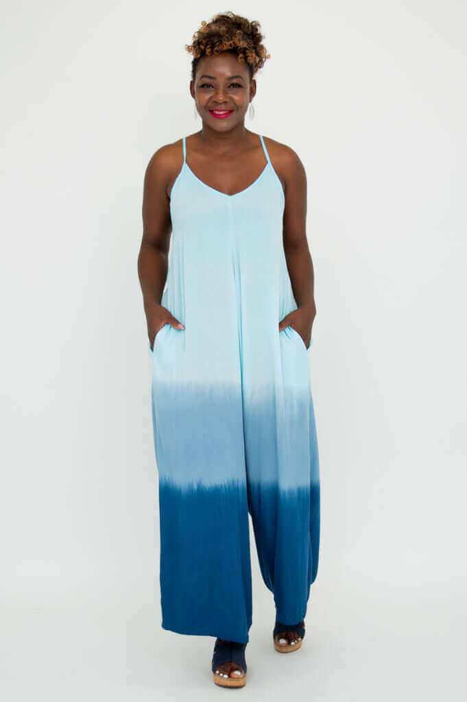 Model with hands in pockets, wearing a blue ombre jumpsuit with v-neckline