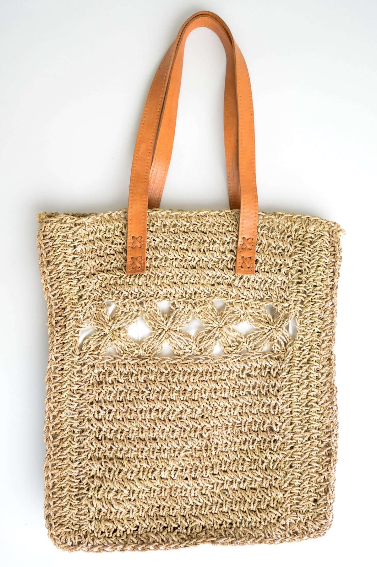 Handwoven rattan tote bag with leather handles and floral crochet detail