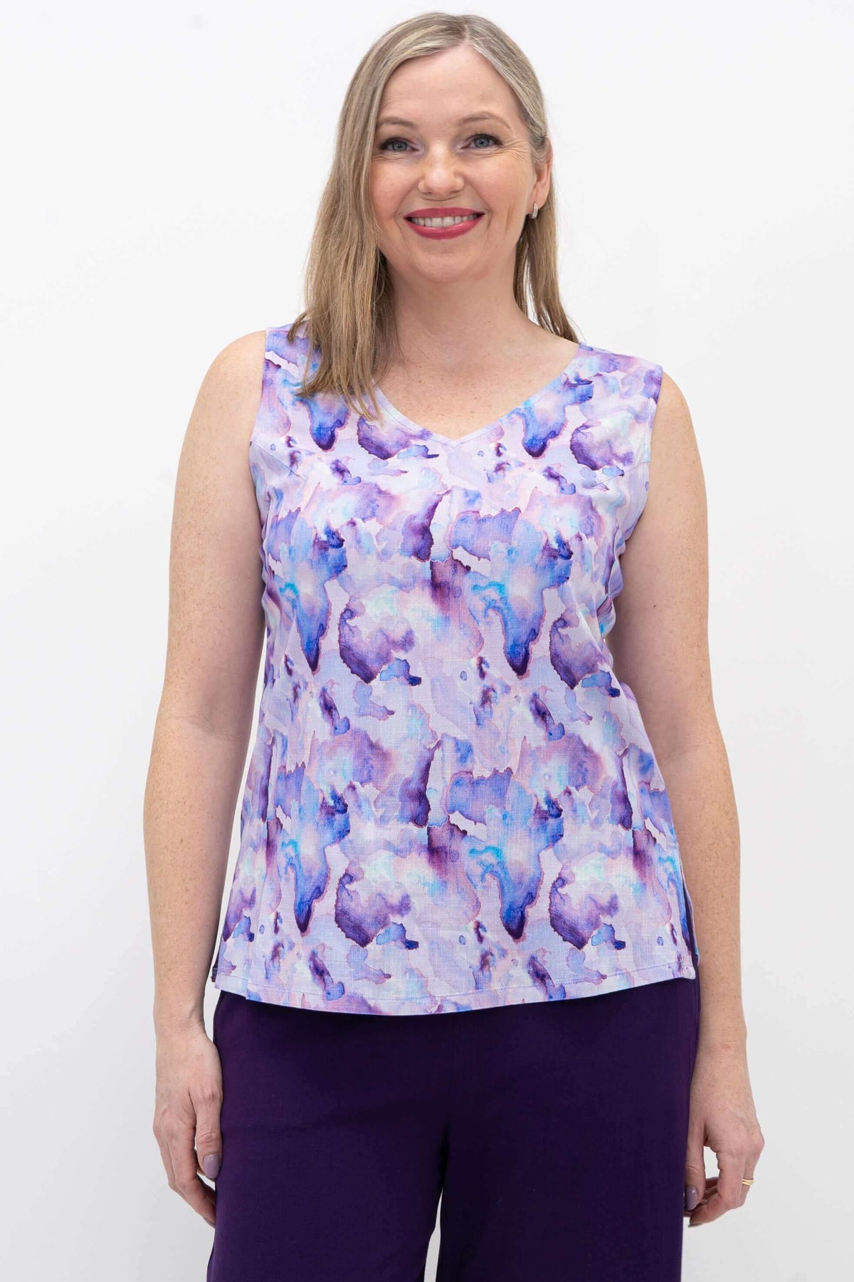 Woman wearing a sleeveless V-neck tank in purple watercolor print, smiling