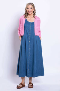 Model with hands in pockets wearing pink cardigan layered over a long blue dress