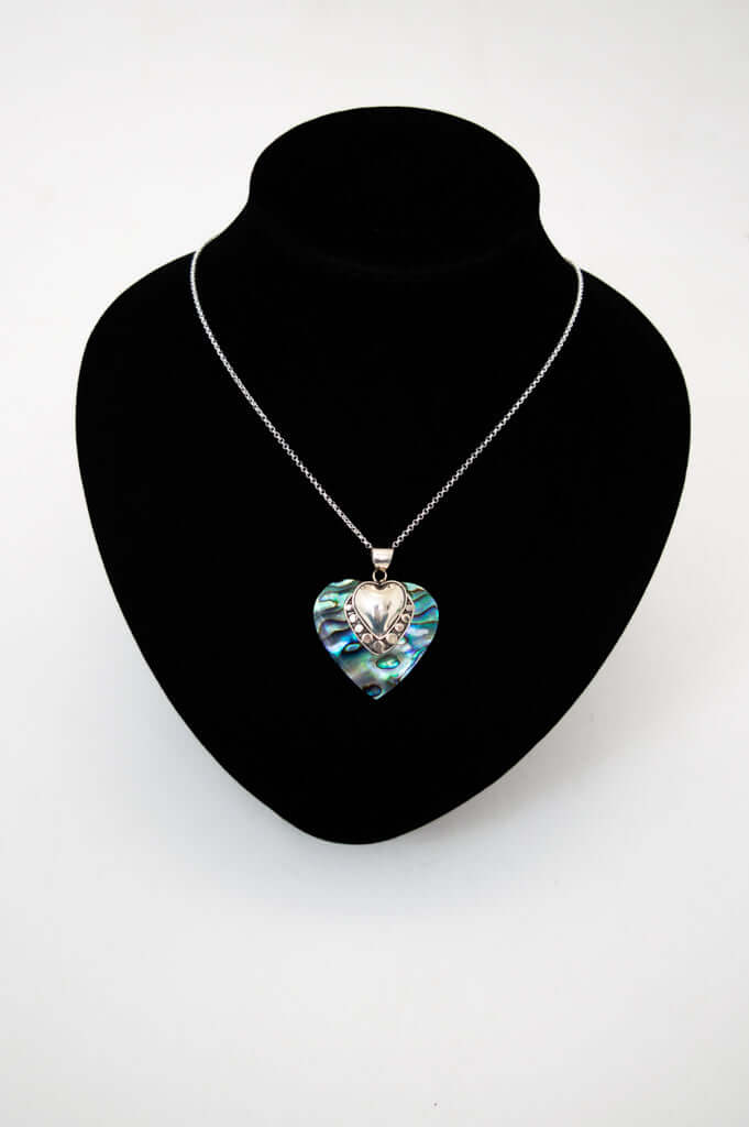 Heart-shaped abalone and silver pendant necklace displayed on a black bust