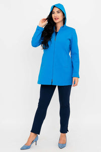 Woman wearing blue coat with hood up, hand raised to touch hood