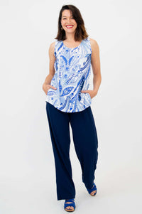 Woman smiling in indigo paisley print tank top and navy wide-leg pants, hands in pockets