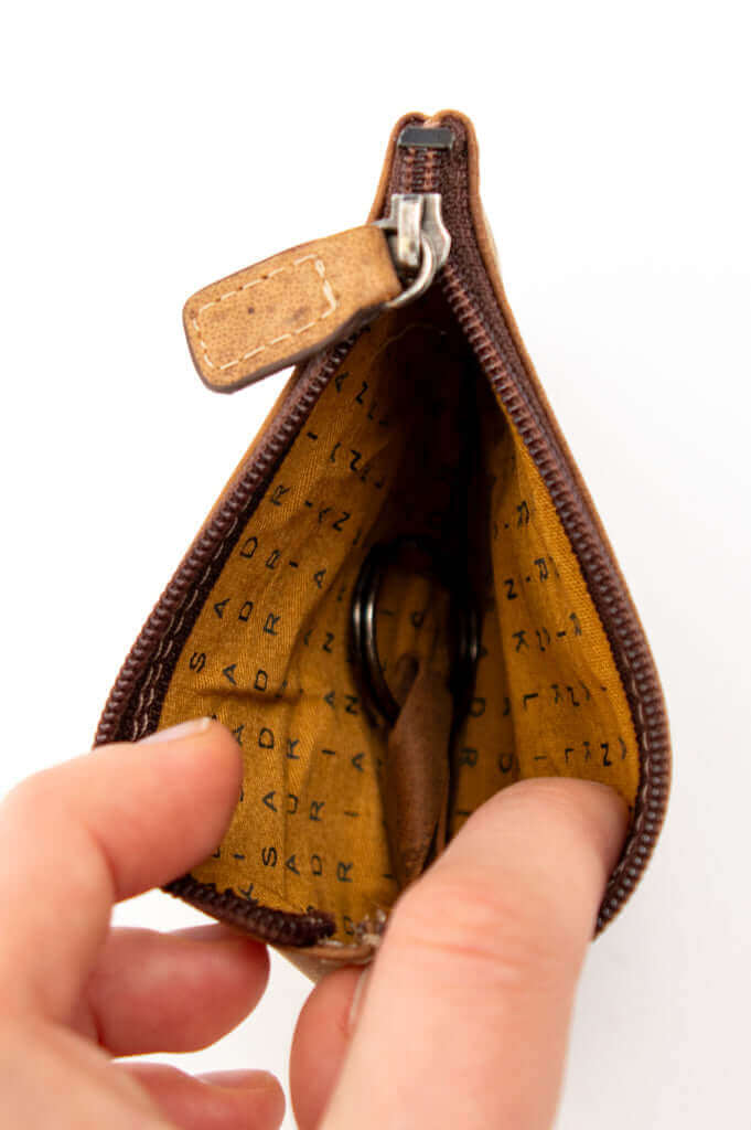 Interior view of brown leather zip wallet showing yellow patterned lining and key ring