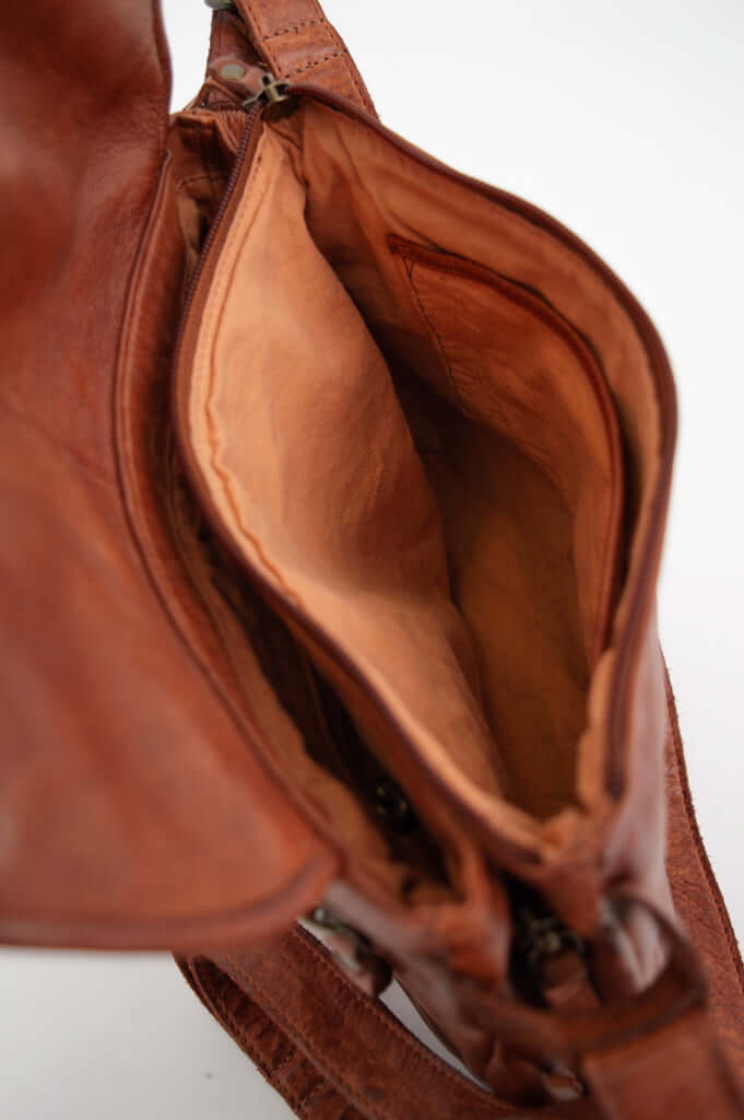 Interior compartment of brown leather messenger bag, showing spacious lining