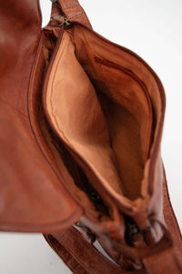 Interior compartment of brown leather messenger bag, showing spacious lining