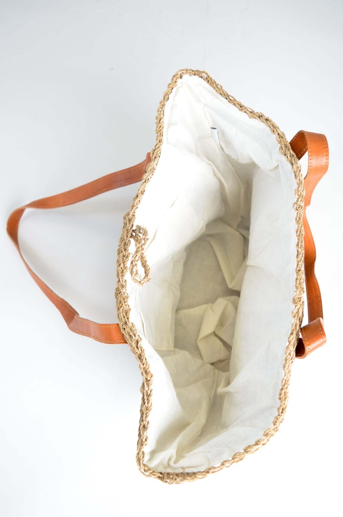 Interior view showing white cotton lining and small pocket inside the rattan bag