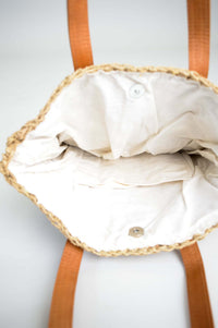 Interior view of rattan tote bag showing white cotton lining and small pocket