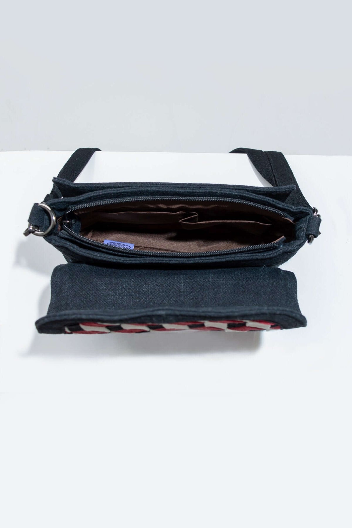 Interior view of black crossbody bag, showing zippered pocket and lining