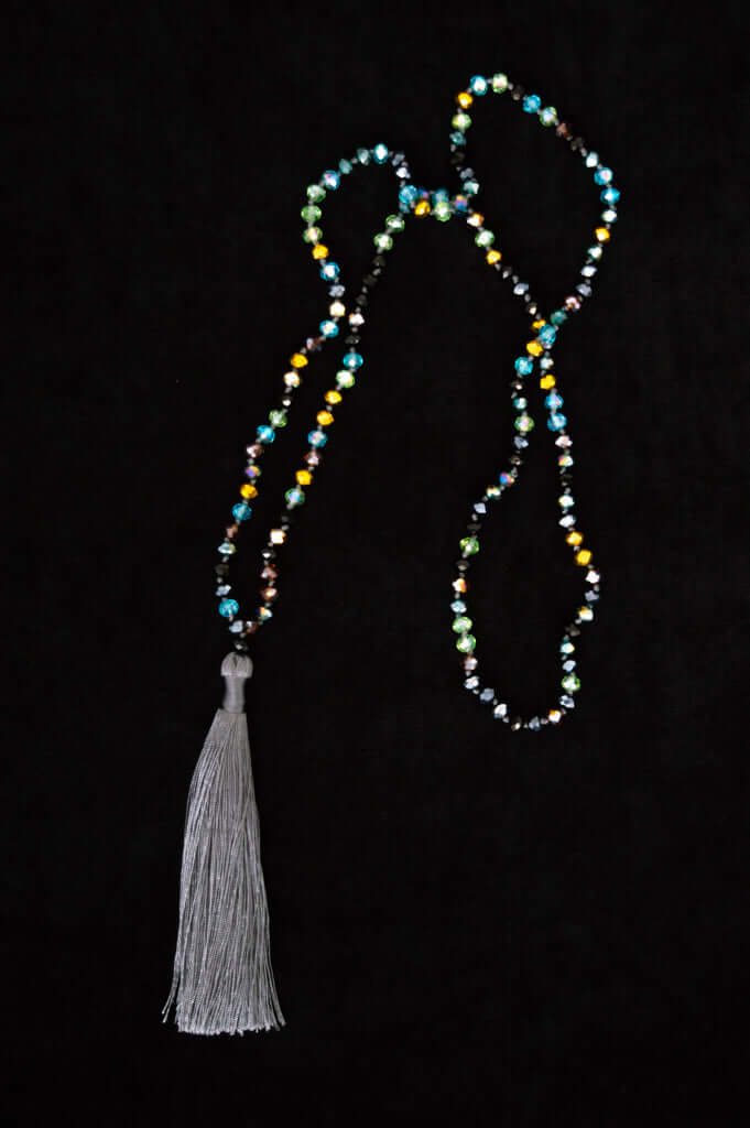 Colorful beaded necklace with a long gray tassel against a black background
