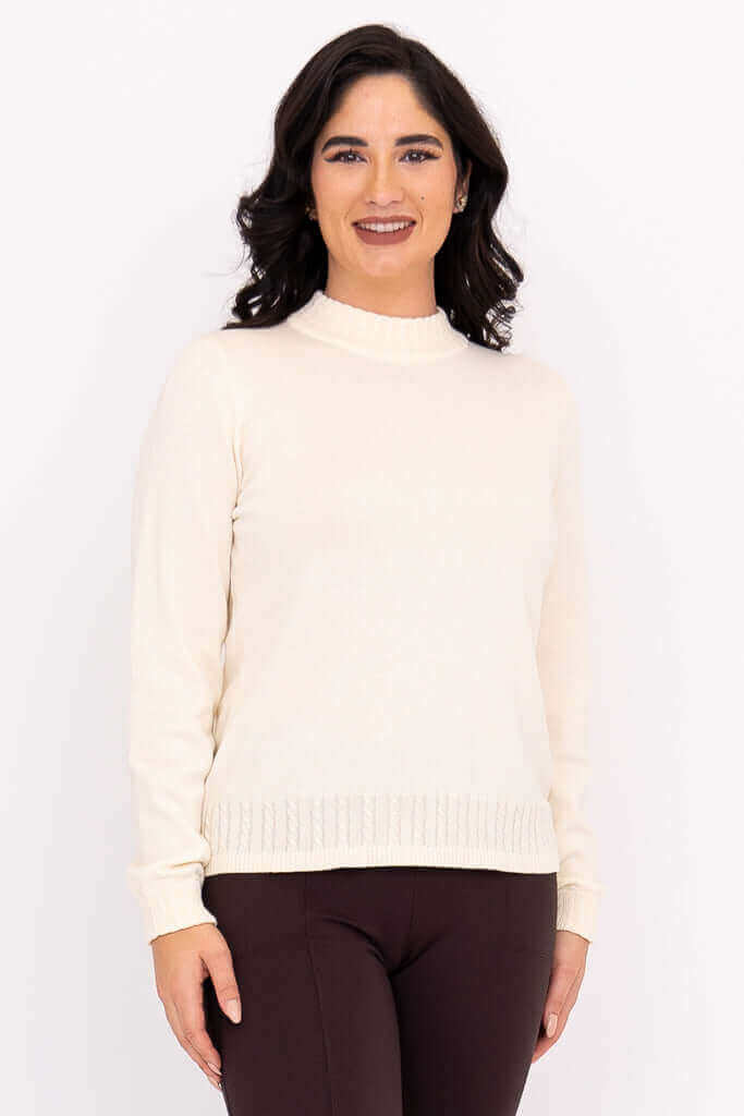 Woman wearing an ivory mock neck sweater with cable knit details, front view