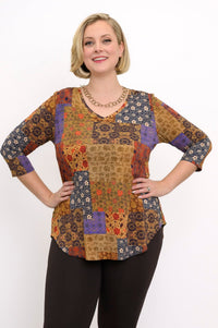 Model wearing a yellow and brown patterned V-neck bamboo tunic and brown pants, standing against a white wall.