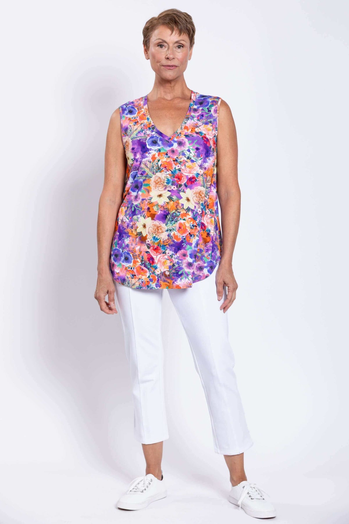 Woman standing front-facing wearing a sleeveless floral top with white cropped pants