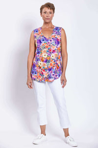 Woman standing front-facing wearing a sleeveless floral top with white cropped pants