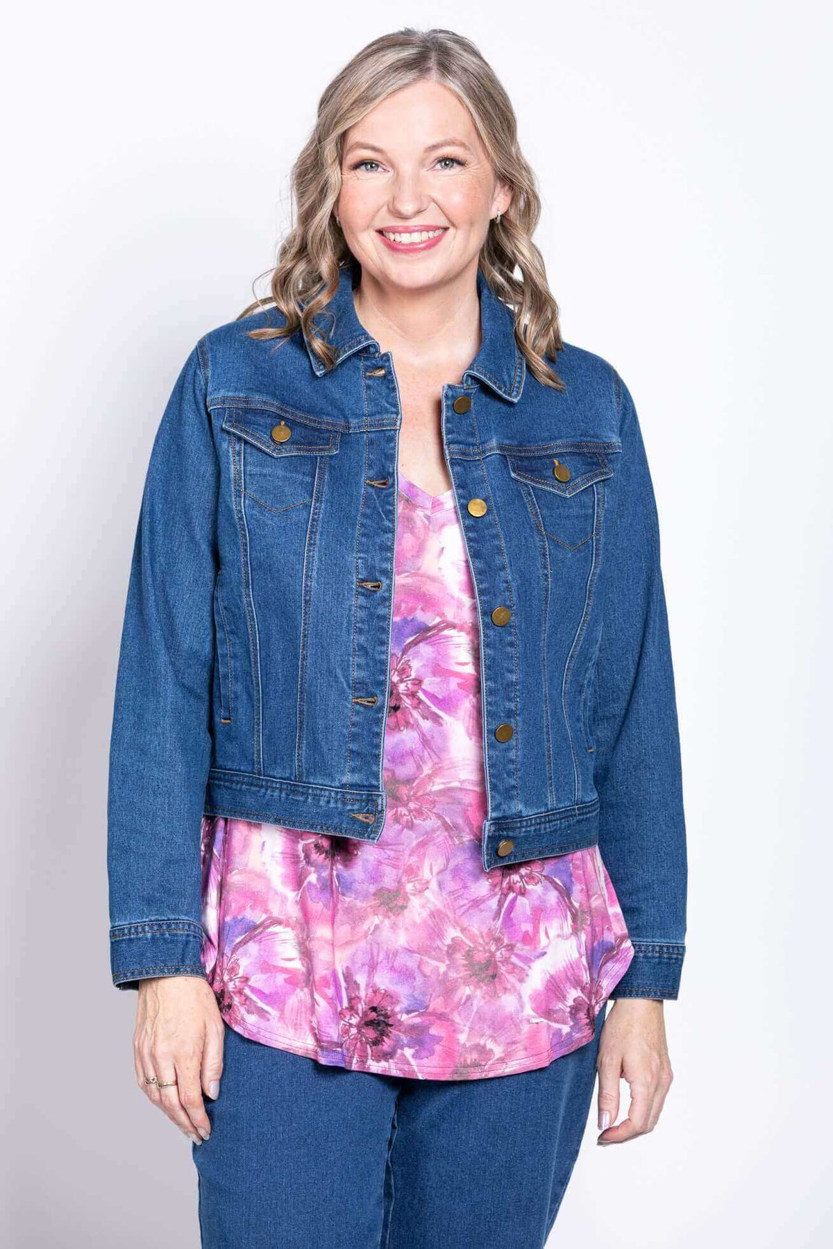 Woman wearing a denim jacket over a pink floral V-neck bamboo top and jeans