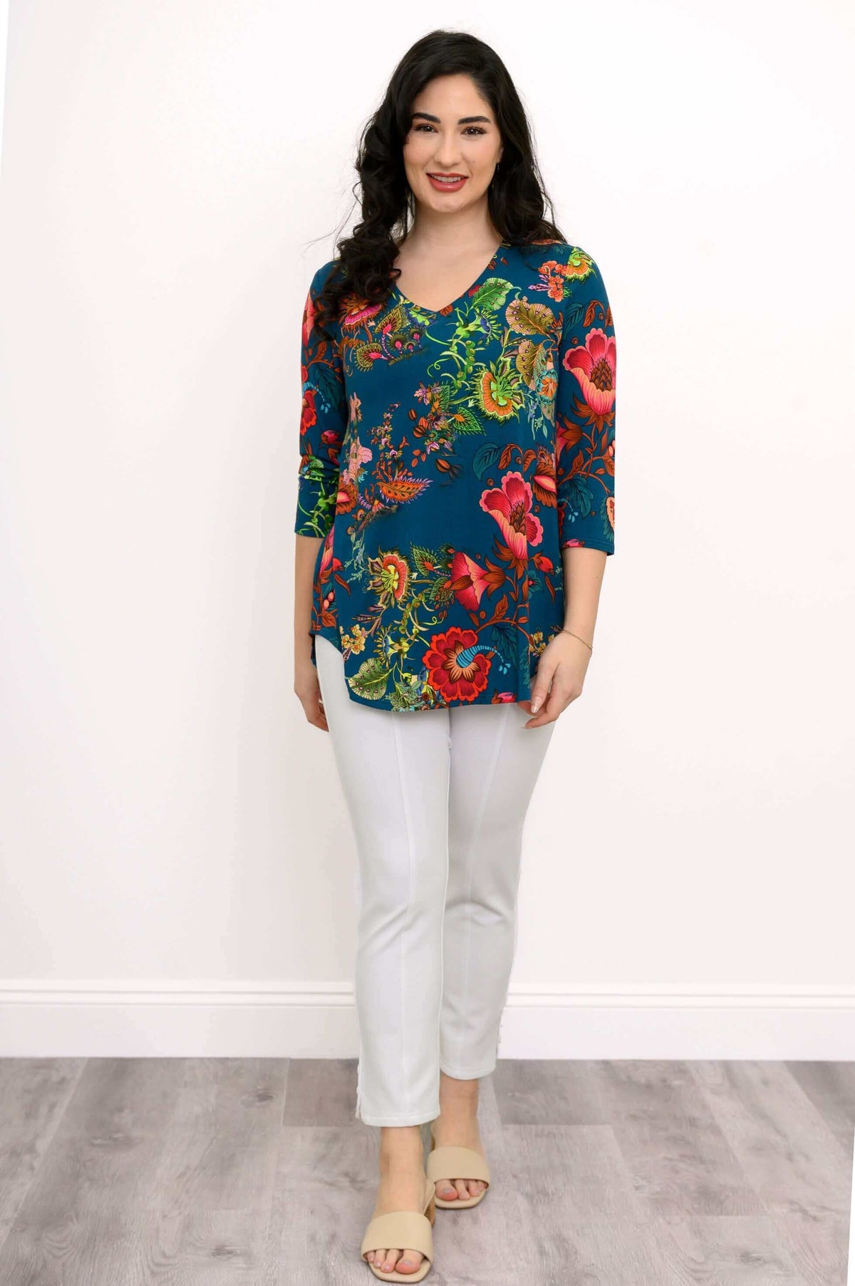 Full body front view of woman modelling v-neck teal top with bright floral print