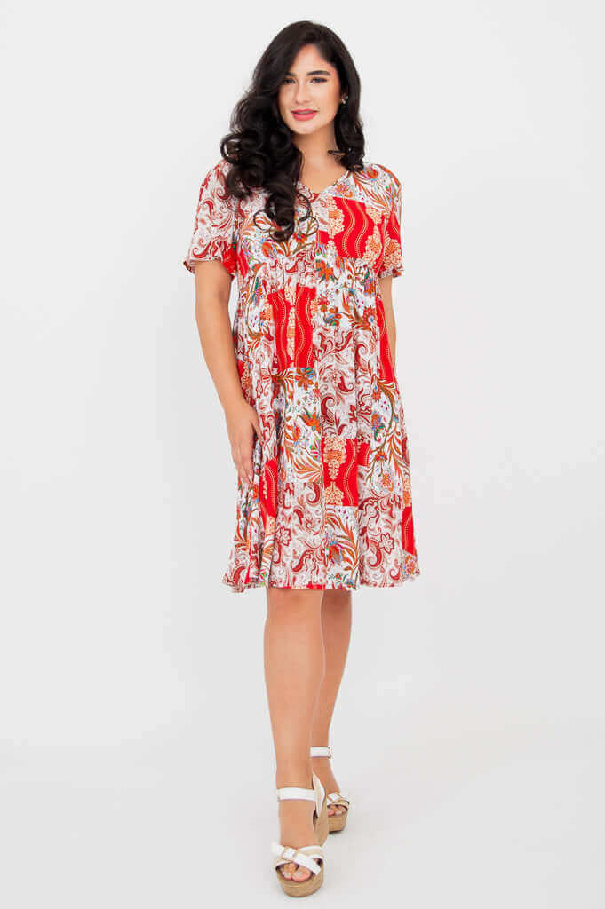 Woman modeling a vibrant red and white patchwork dress with a v-neck and flutter sleeves