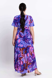 Back view of woman in purple maxi dress with flowing skirt and flutter sleeves