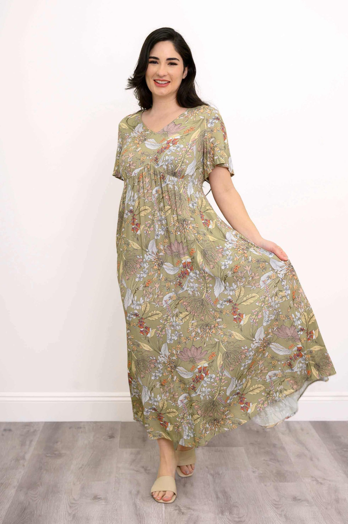 Woman holding out the skirt of a floral maxi dress and smiling