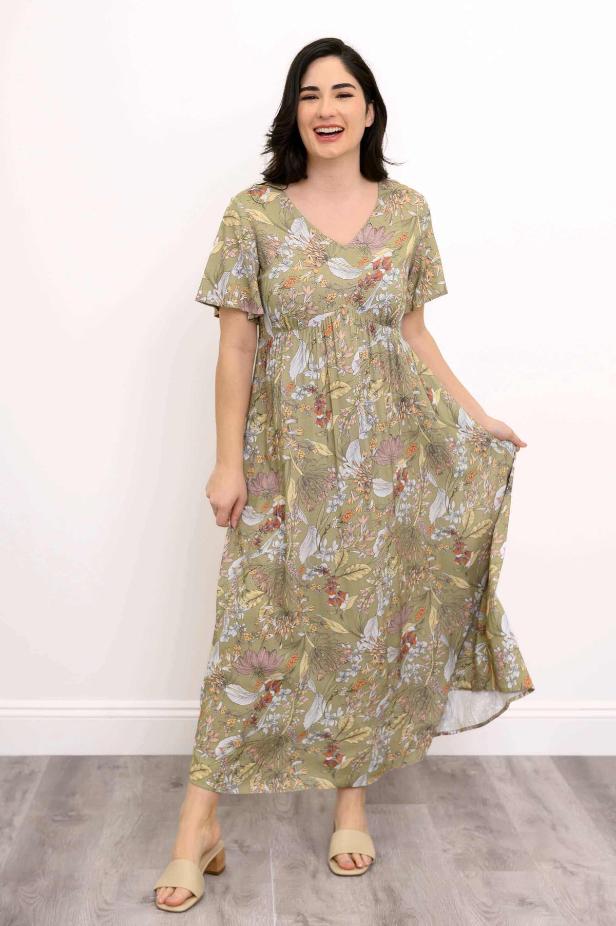 Woman laughing in a long green floral dress with empire waist and flutter sleeves