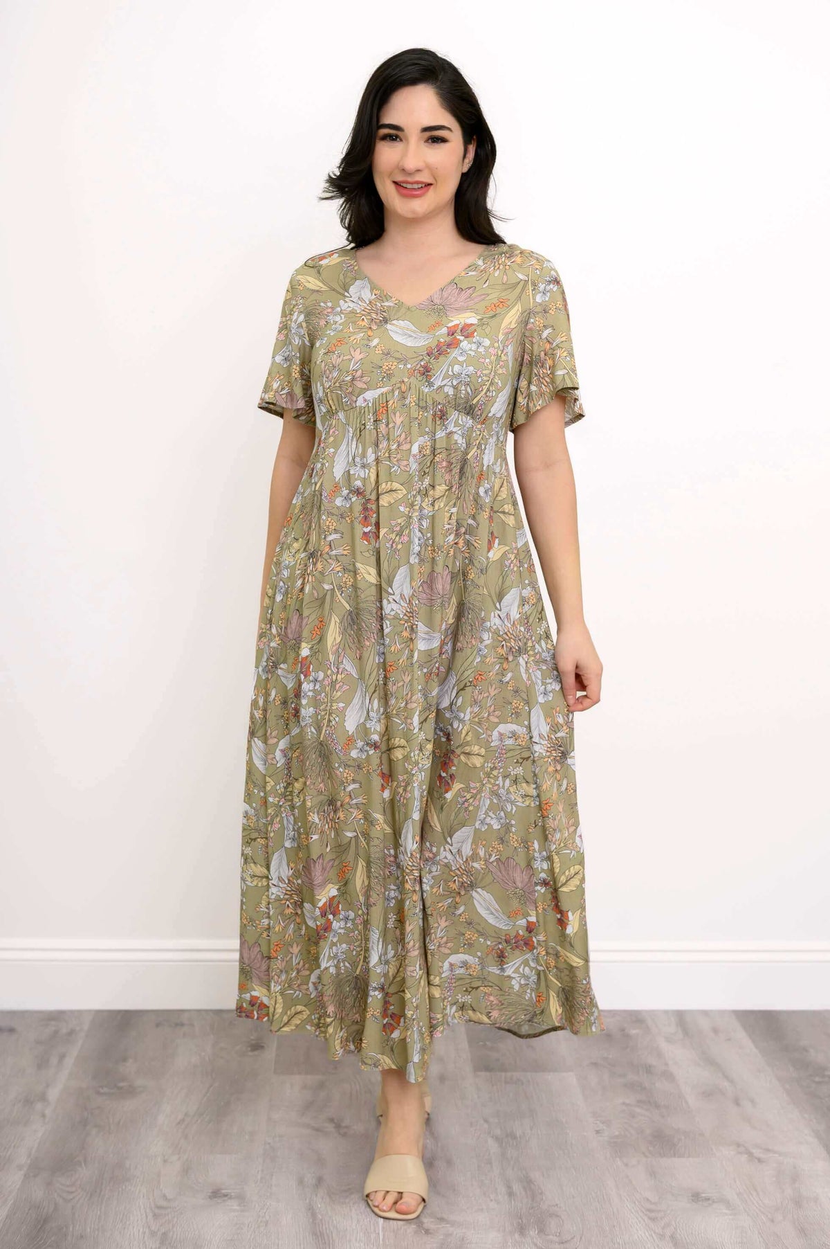Woman in green floral empire waist maxi dress standing straight