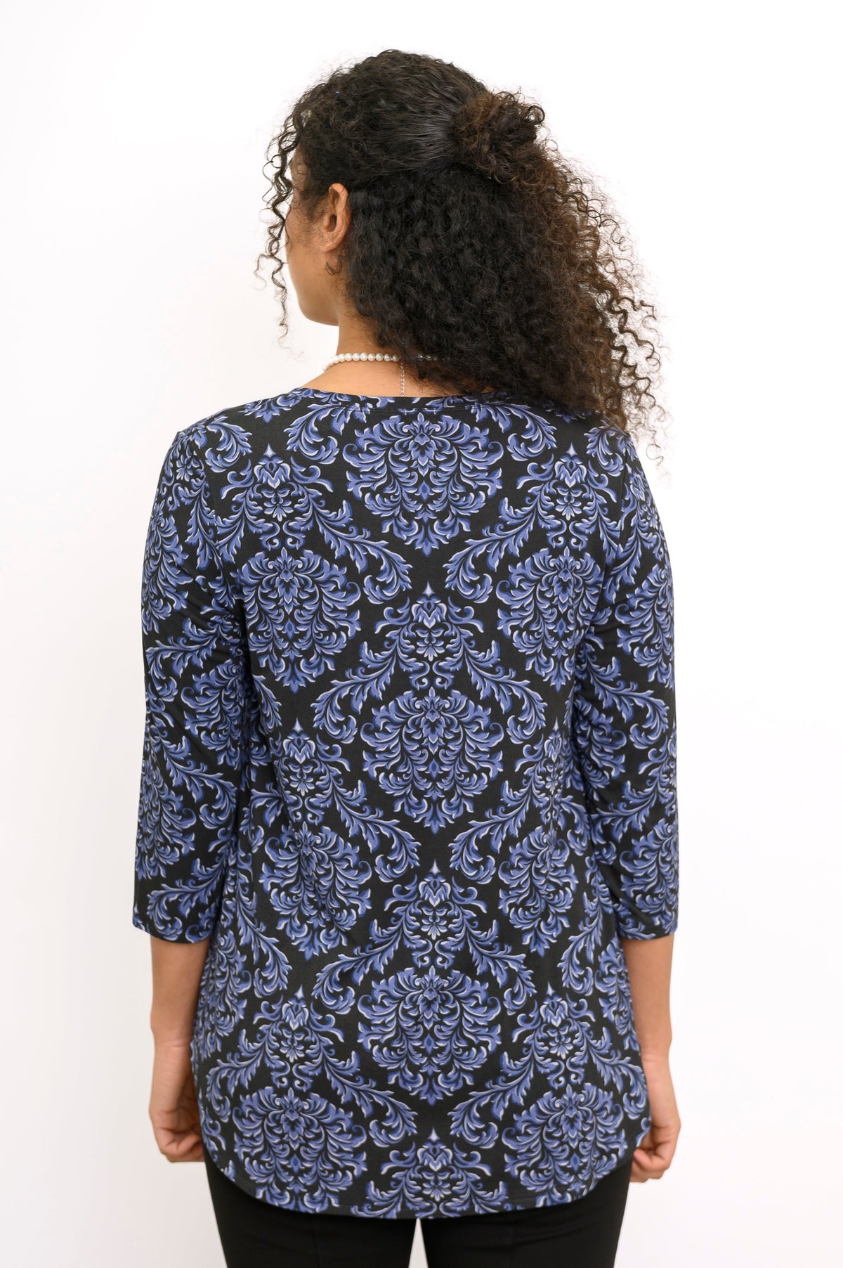 Back view of a woman wearing an indigo patterned 3/4 sleeve bamboo top with a clean shoulder fit.