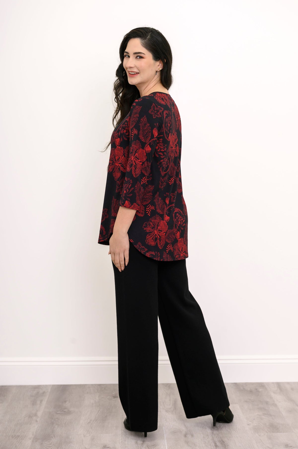 Back view of a red and black floral print bamboo top, illustrating a loose, hip-covering length and rounded hem.