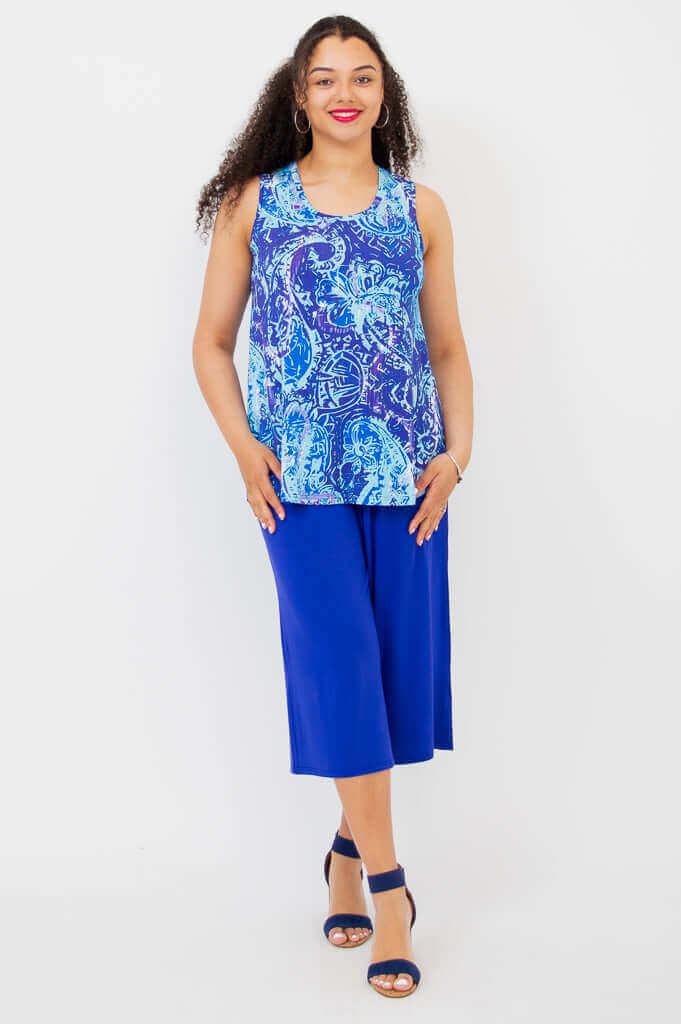 Full view of woman wearing a blue batik tank top with wide-leg blue pants and heels