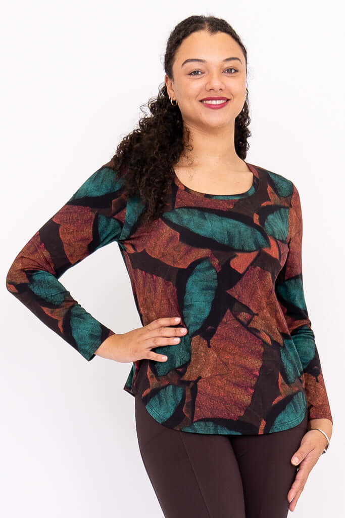 Close-up of model wearing Jazz top with abstract teal and rust leaf print