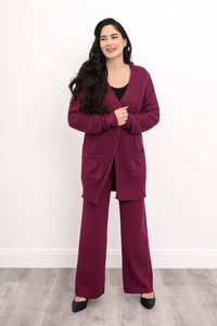 Front view of a woman wearing an extra coverage raspberry pink cable knit cardigan top.