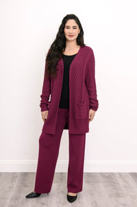 Three quarter view of a woman modeling a comfortable raspberry pink cable knit sweater for fall layering.