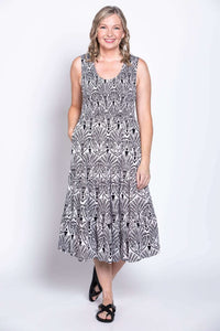 Woman smiling in sleeveless black and white patterned dress, front angle view