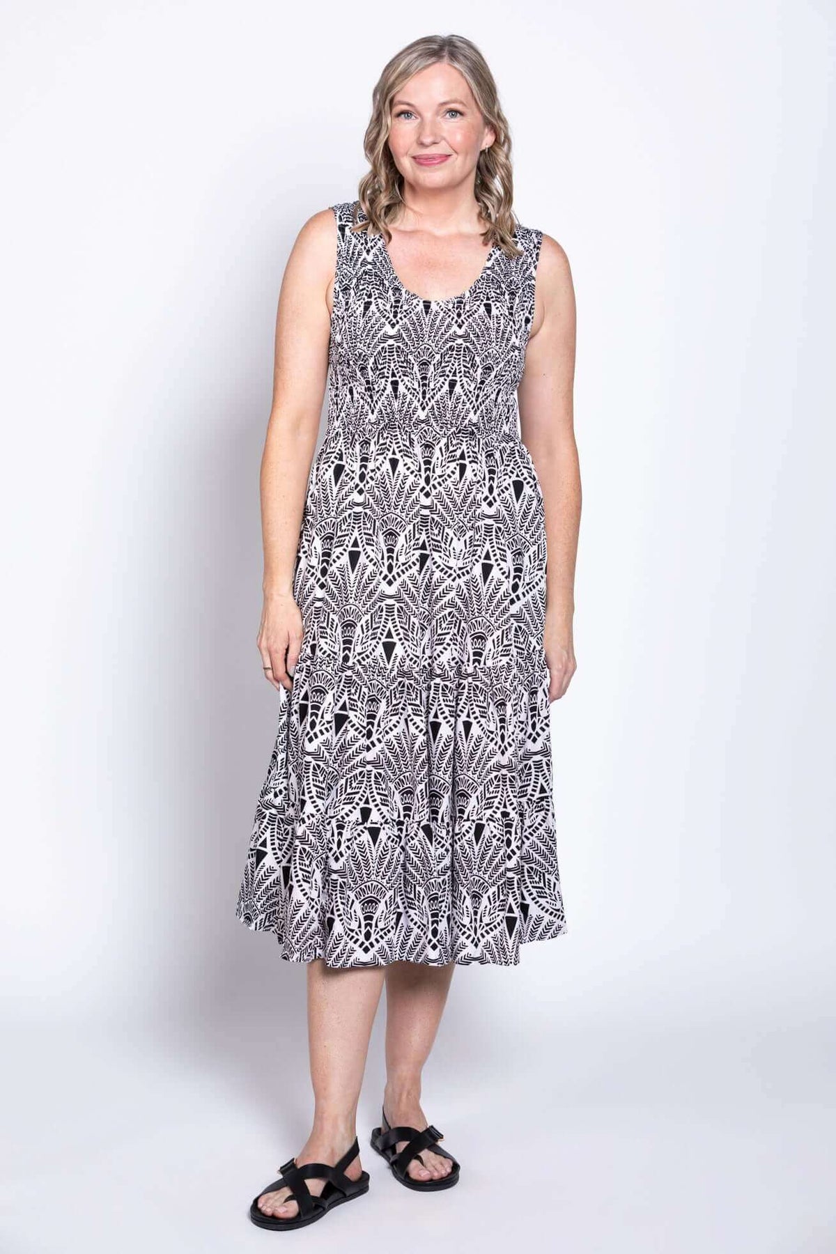 Woman posing in sleeveless black and white tiered dress with side pockets