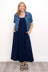 Front view, woman wearing blue jacket, navy blue jumpsuit, and sandals against a white background